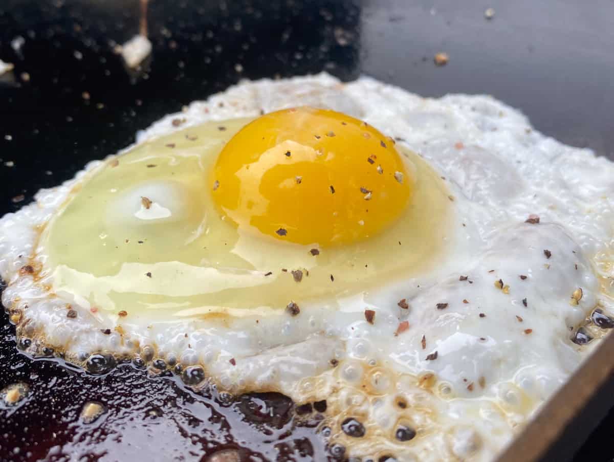 Close up of fried egg with uncooked yolk and sprinkled with pepper