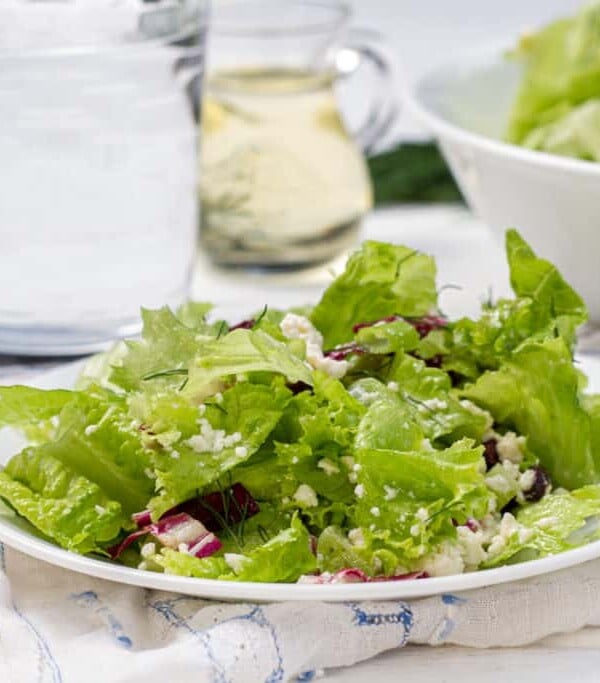 A Marousalata Salad on a plate with a bowl of salad and glass of water.