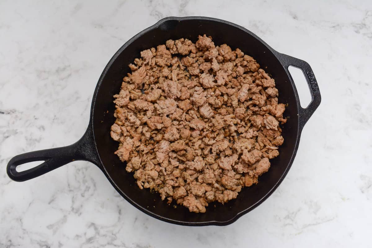 A cast iron skillet with cooked ground turkey 