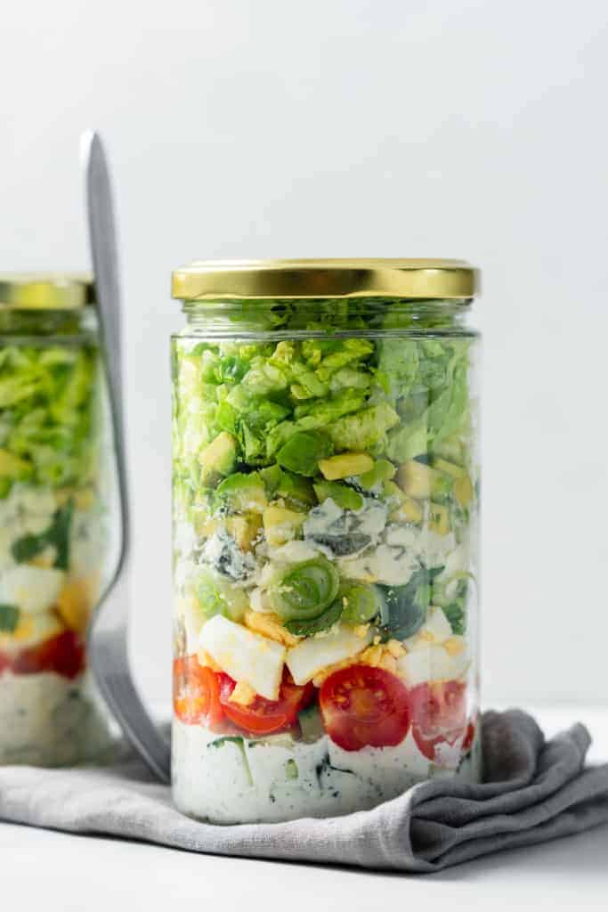 A Vegetarian Cobb Salad in a gladd jar on a napkin.