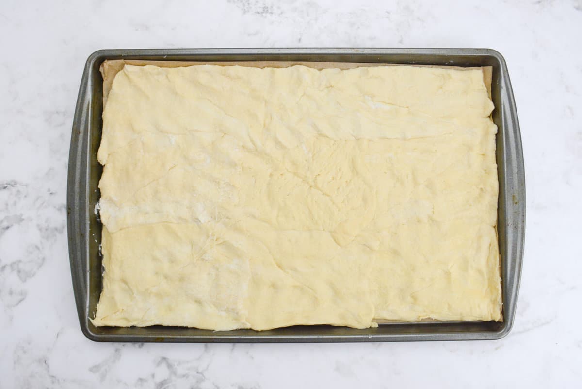 A baking sheet lined with parchment and the dough pressed into a flat layer 