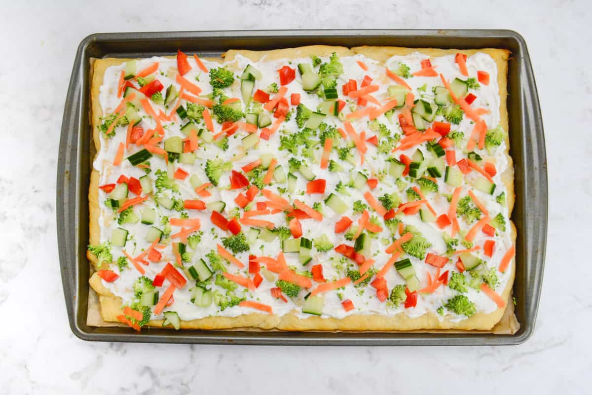 A baking sheet with the finished pizza topped with all of the chopped vegetables 