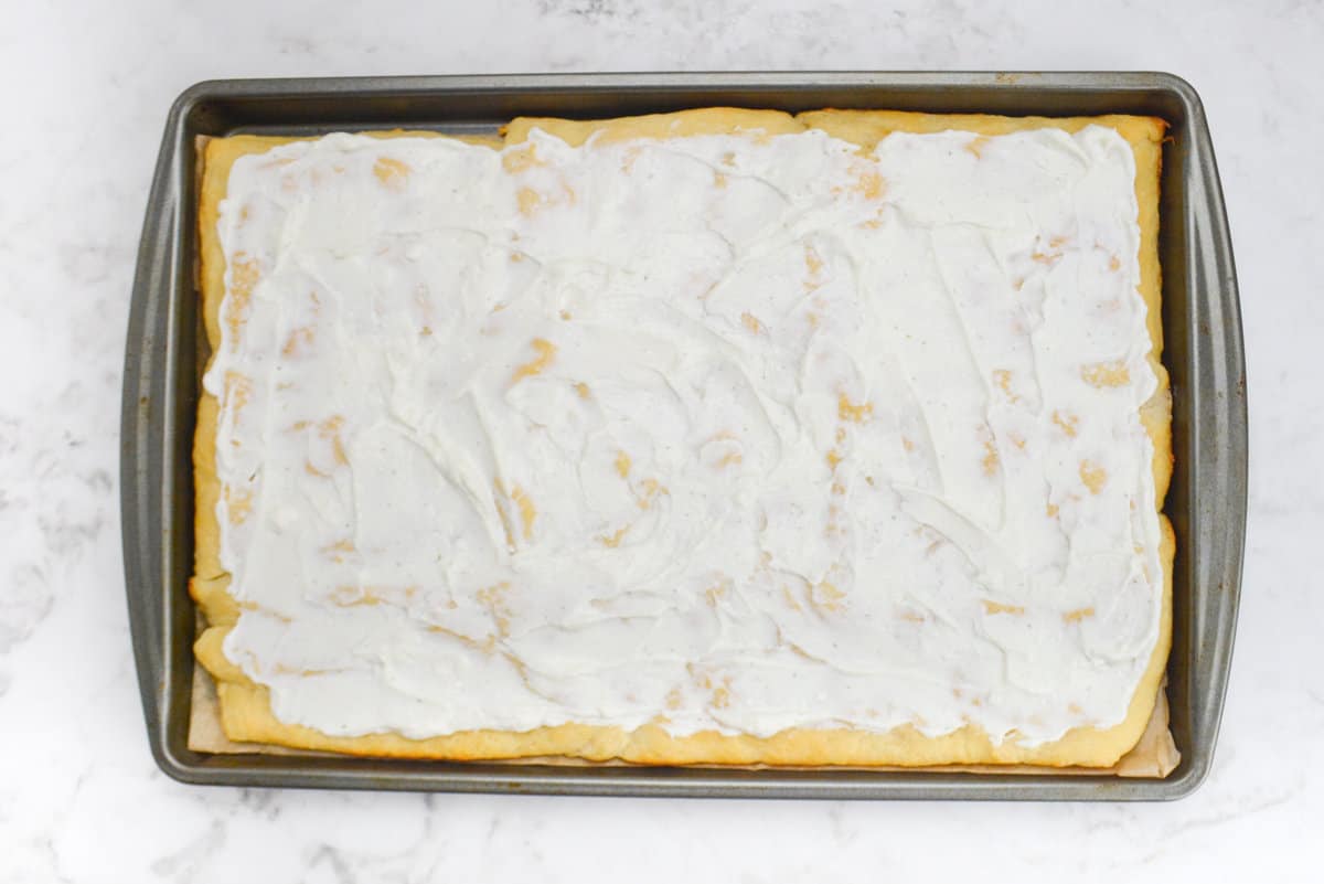 A baking sheet with the baked dough and a layer of cottage cheese ranch spread 