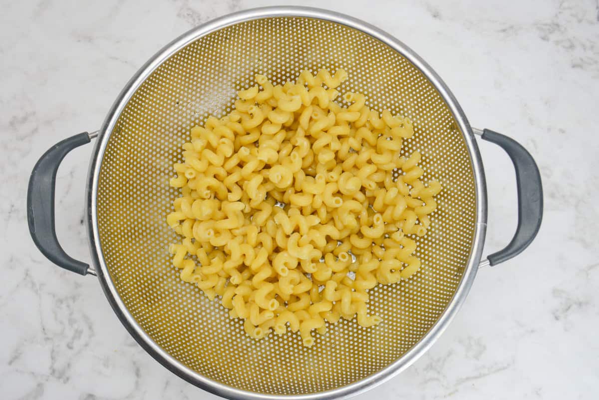 A large silver colander filled with drained cooked pasta 