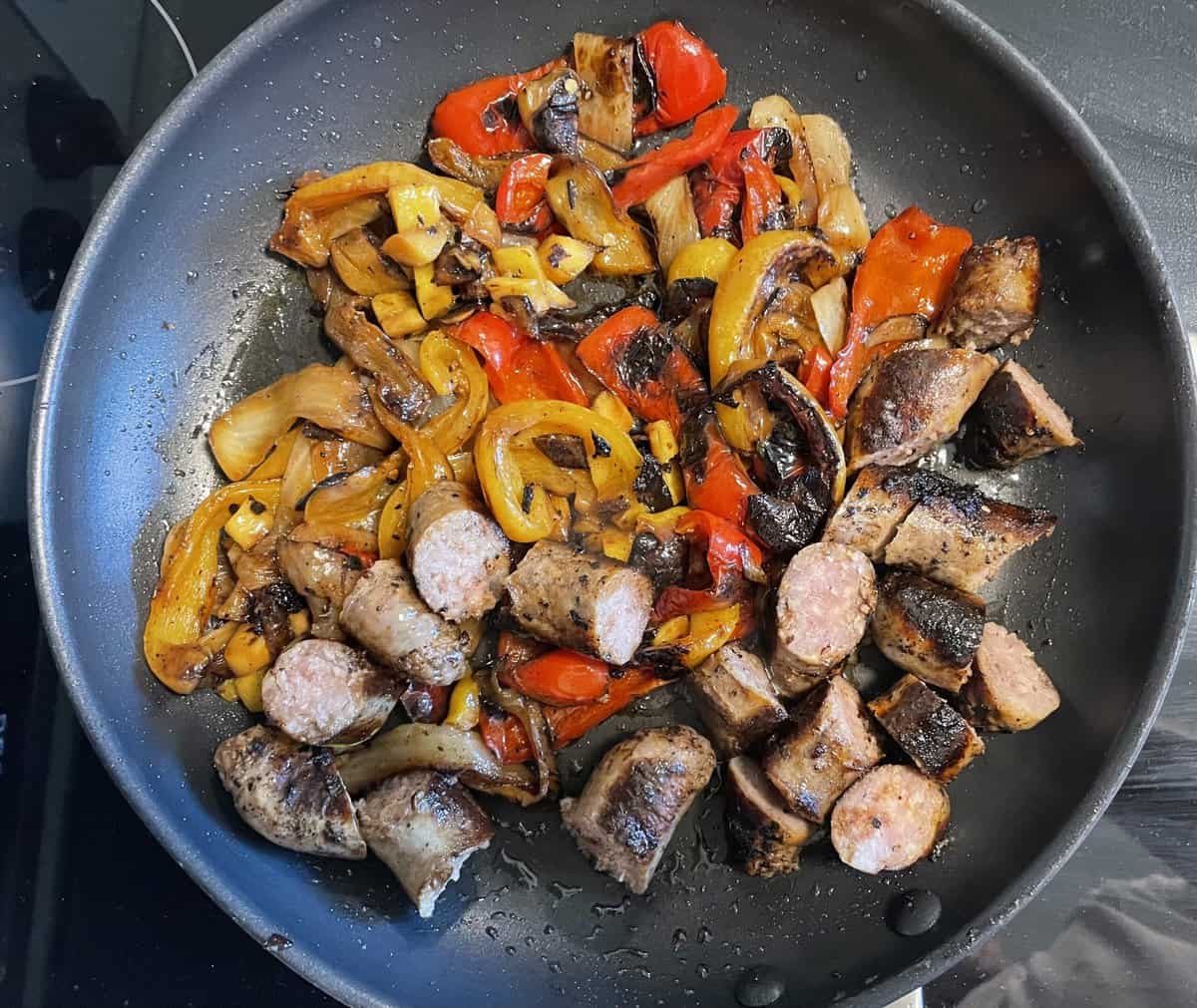 sausages and peppers cooking in a pan