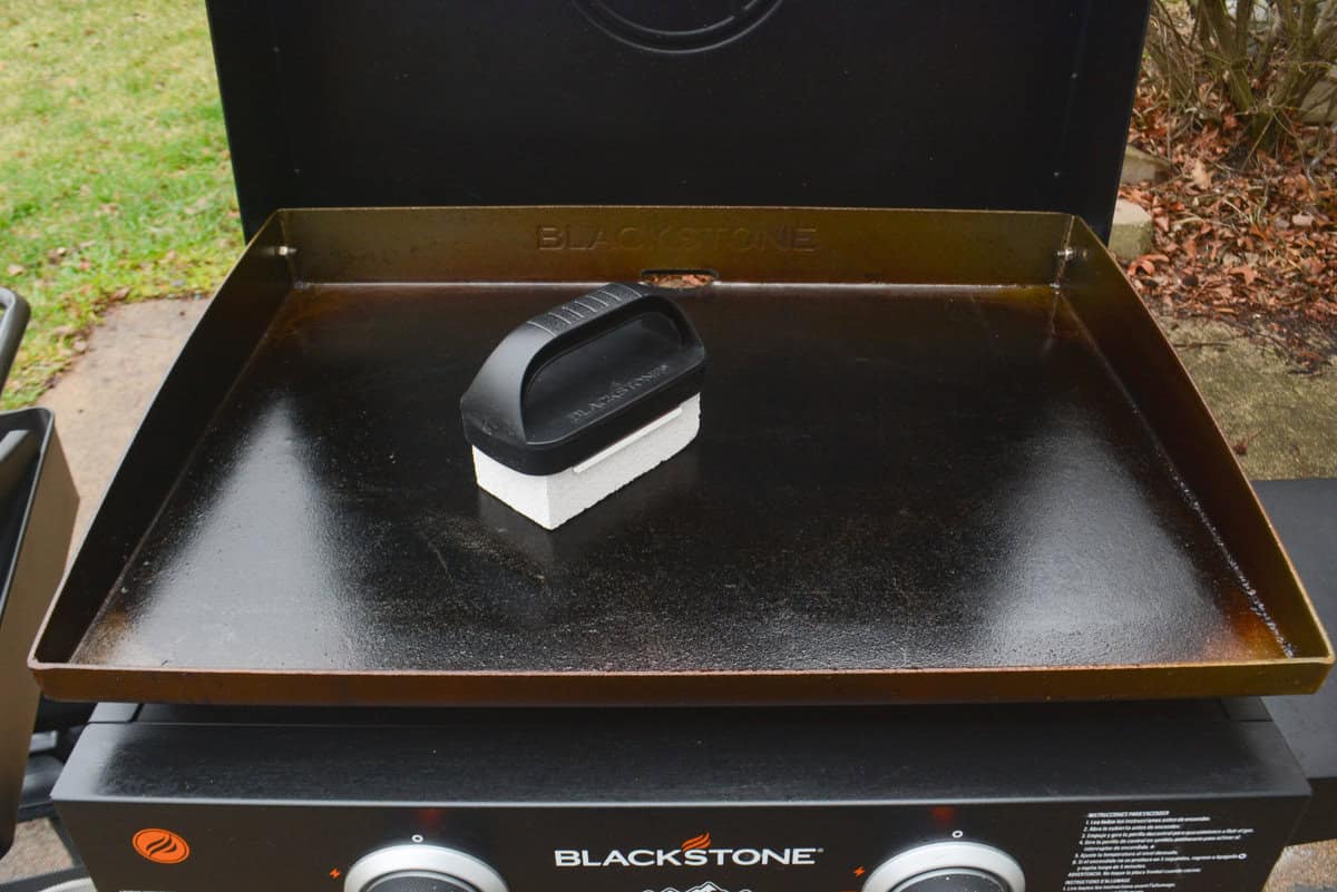 An open griddle with a grill brick sitting on top