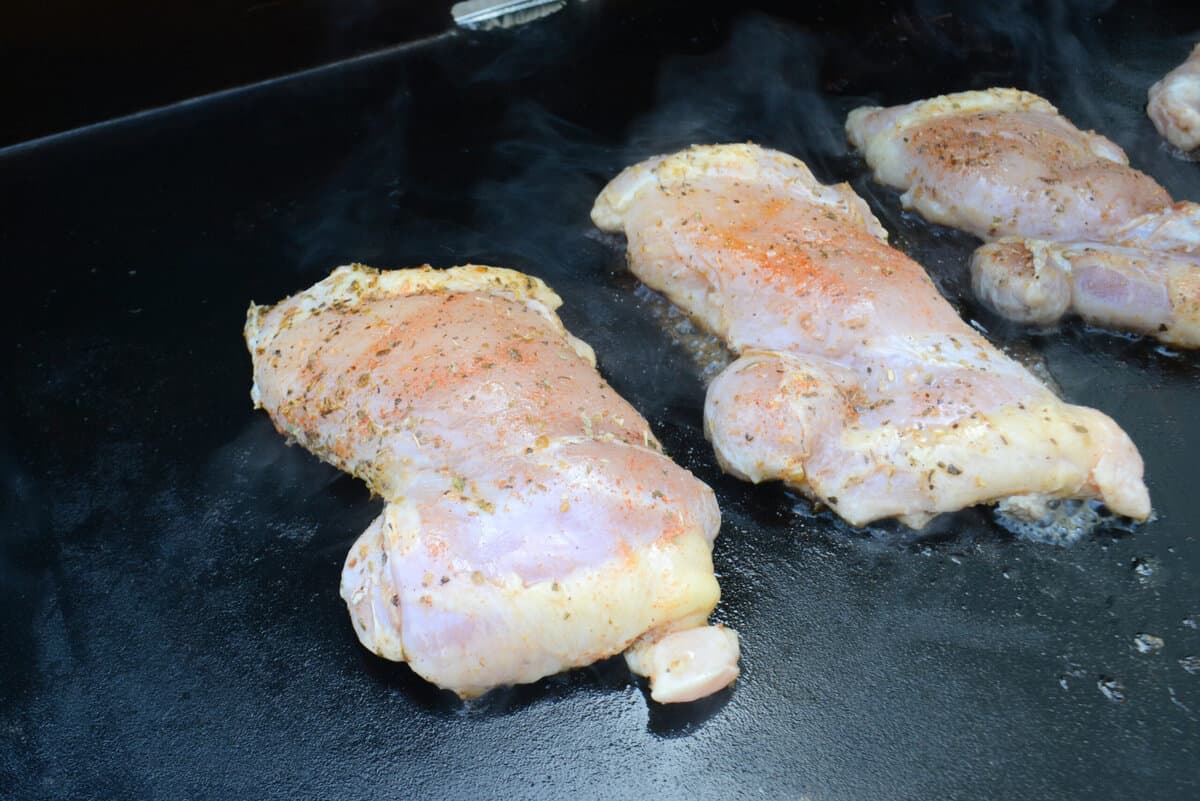 Close up of three chicken thighs cooking on the Blackstone