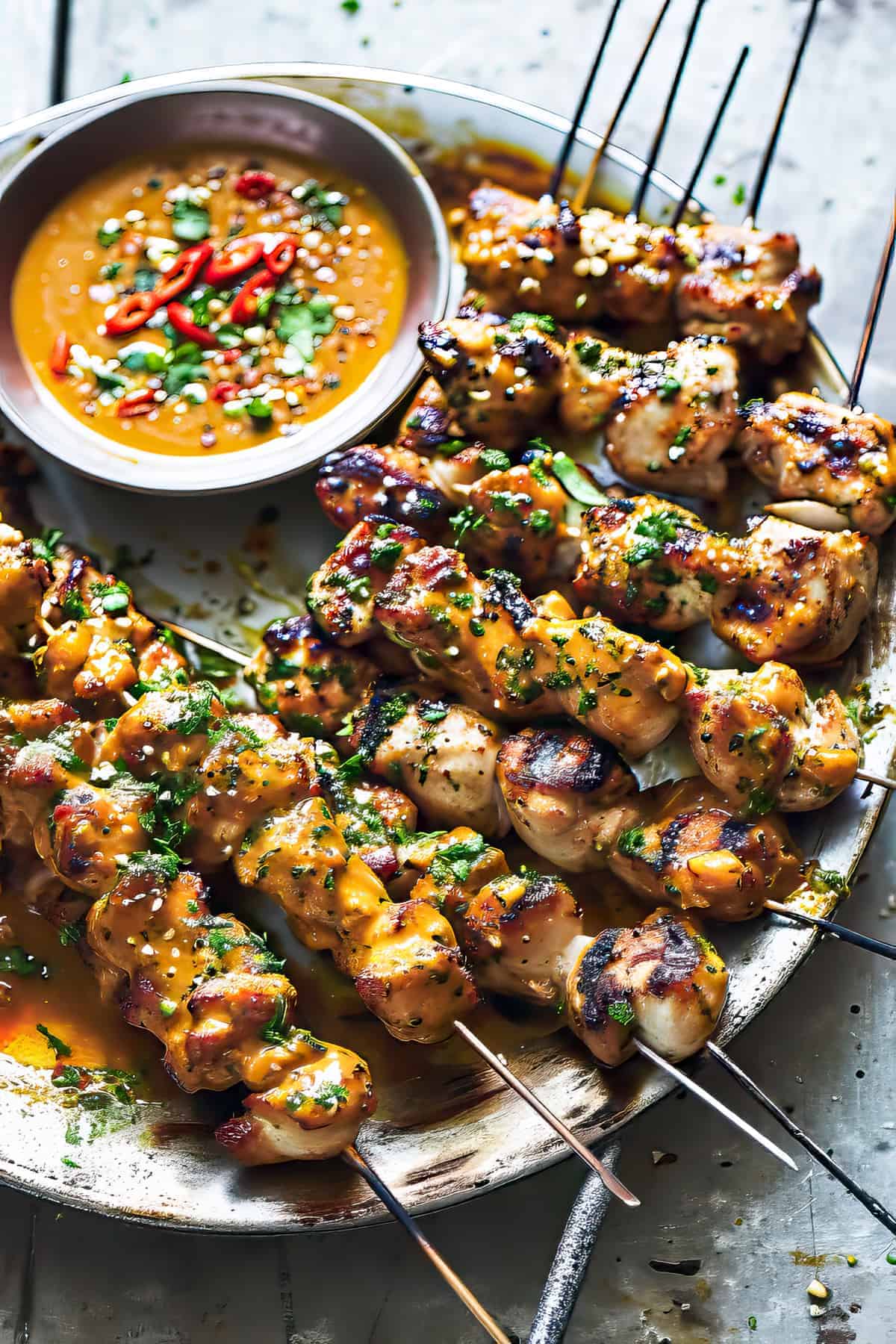Thai coconut chicken skewers with spices on them on a plate with a dipping sauce.