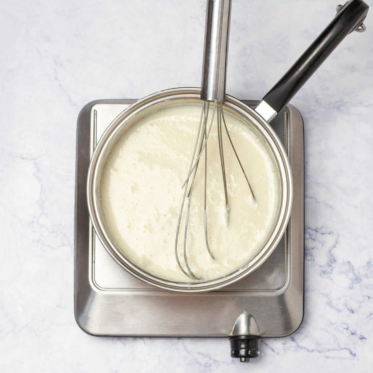 Bechamel Sauce in a saucepan with a whisker