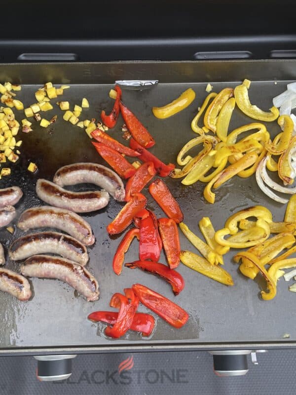 sausages and peppers cooking on a blackstone