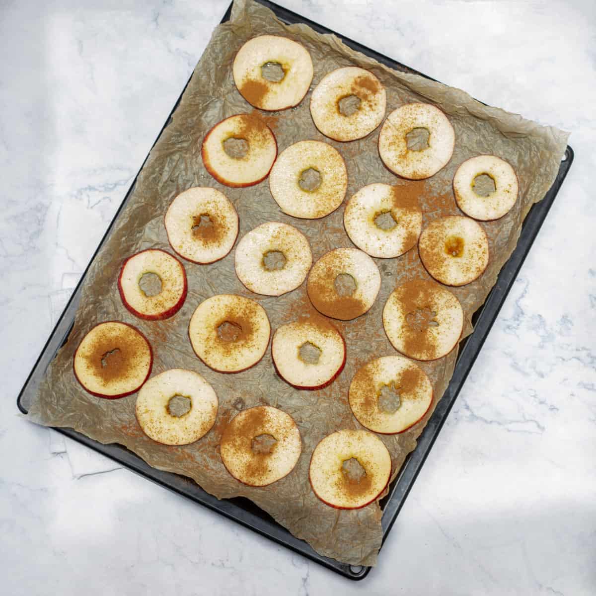 The seasoned apple slices arranged on a baking tray