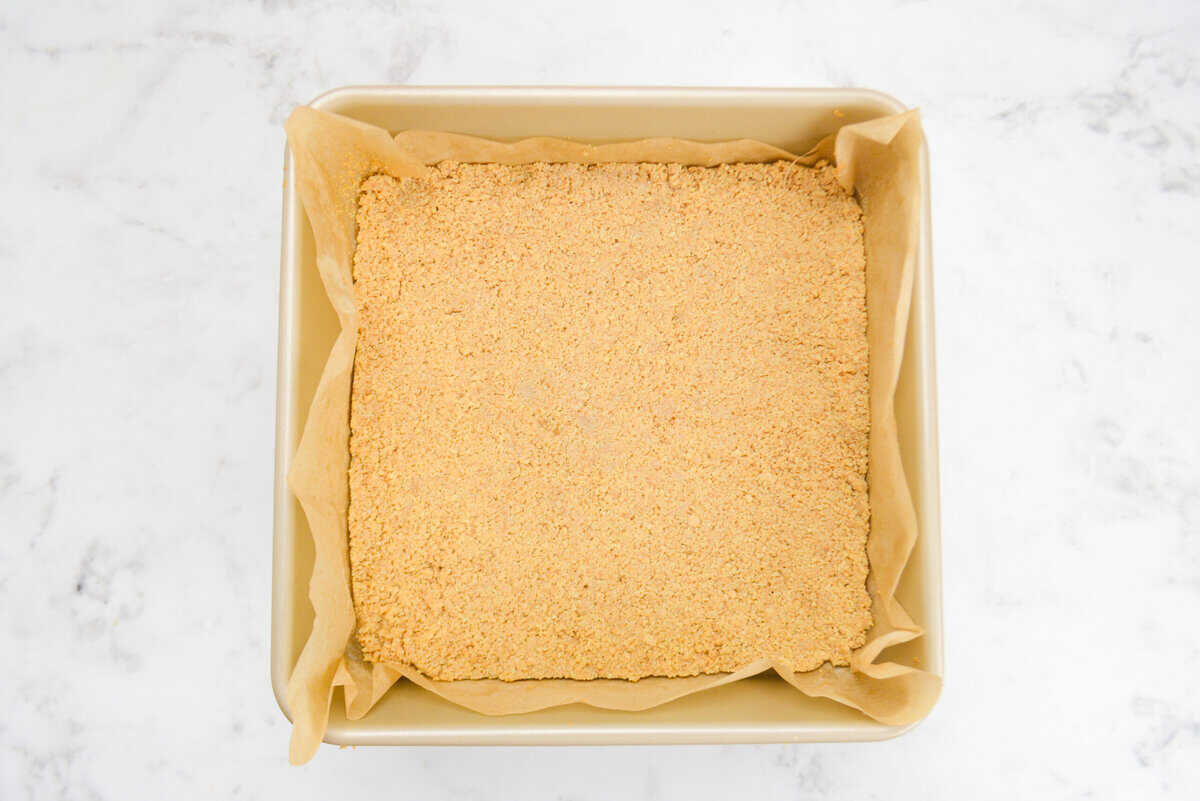 A gold square baking dish with the baked firm crust