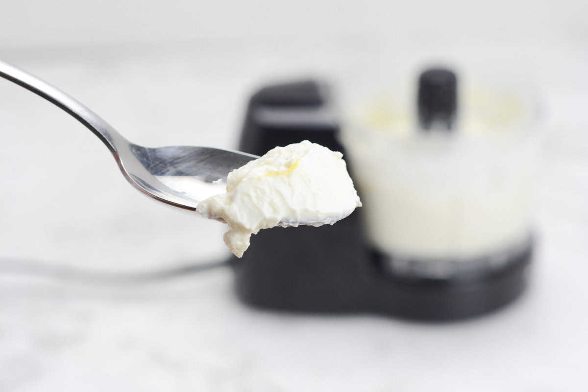 A close up of a spoon filled with the whipped dip. In the background is a food processor. 