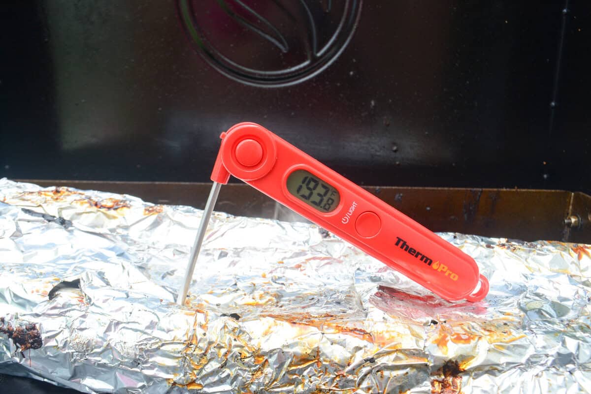 A red thermometer reads 193.8 degrees poked into the foil rib packet.