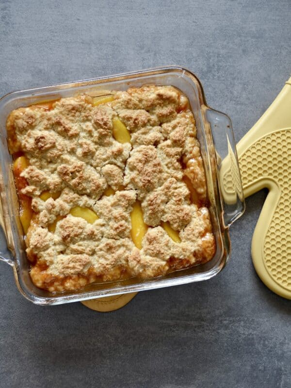 Baking dish with peach cobbler and oven mitt