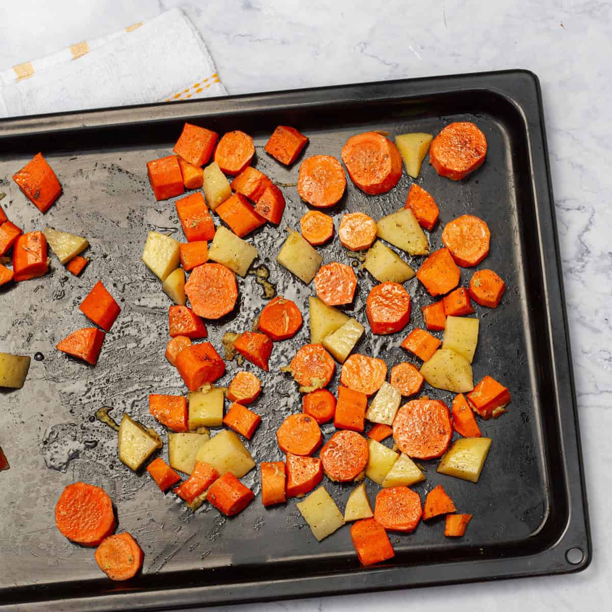 carrots and potato cubes spread in backing tray