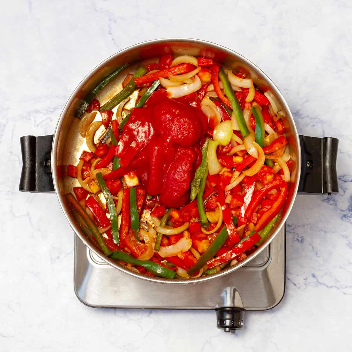 Add tomato paste to the pan with cooked aromatics once their fragrance has been released. 