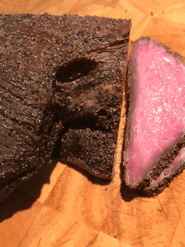 smoked tri tip sitting on wooden cutting board