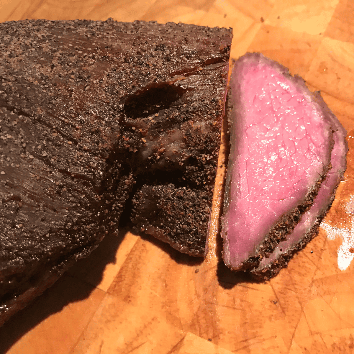 smoked tri tip sitting on wooden cutting board