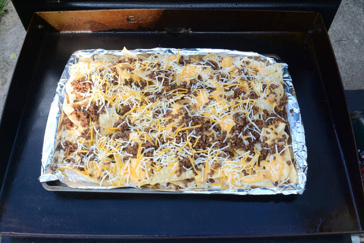An overhead view of the sheet pan. The chips are now covered meat, queso and shredded orange and white cheese