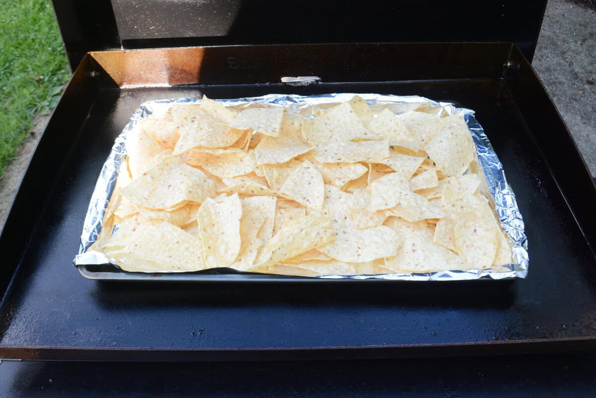 a sheet pan covered in foil and piled with chips sits on the griddle