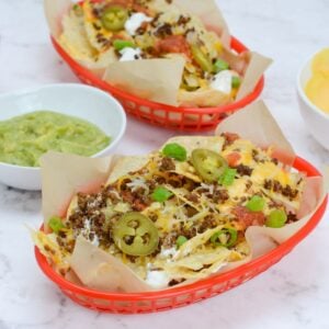 two baskets of blackstone nachos with a variety of toppings.
