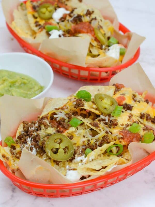 two baskets of blackstone nachos with a variety of toppings.