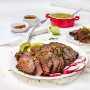 Tender and flavorful carne asada sliced on a platter with fresh radish.