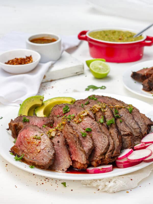 Tender and flavorful carne asada sliced on a platter with fresh radish.