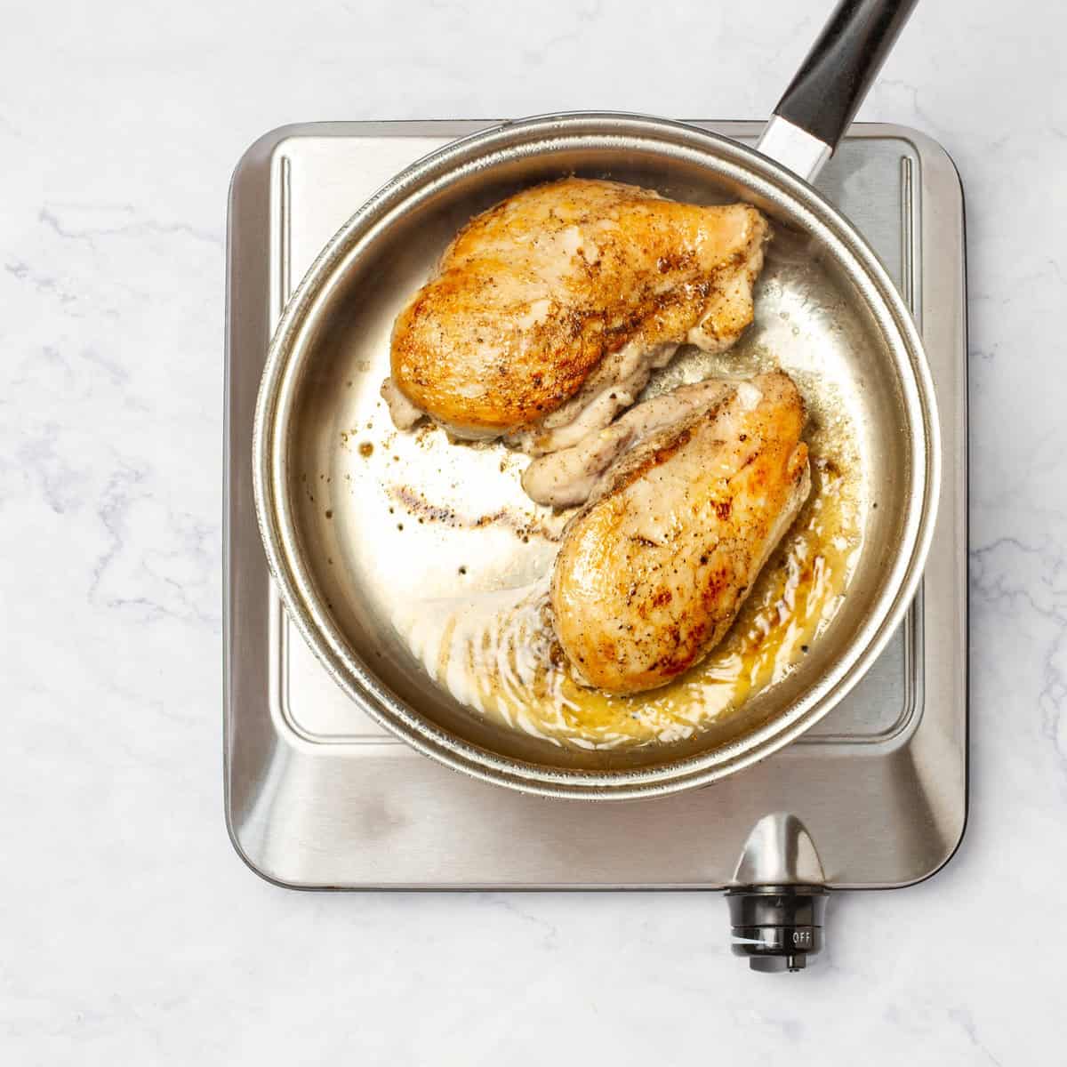 Chicken breasts searing in a pan. 