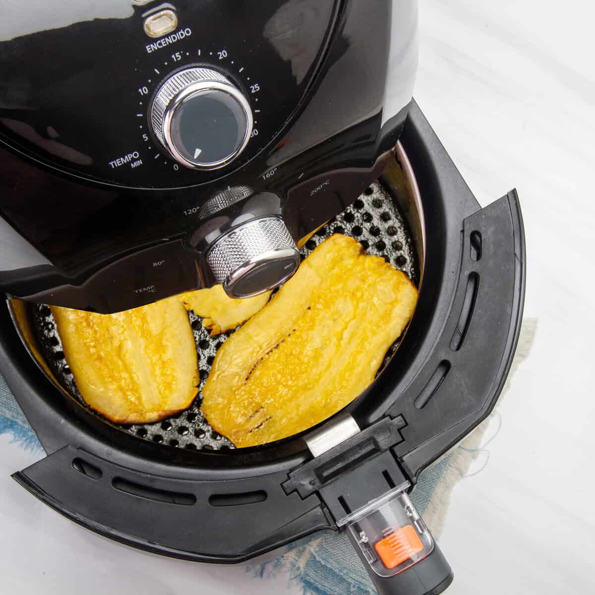 Flattened plantain slices in the air fryer basket for the final fry. 