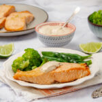 Flakey and succulent Air Fryer Salmon filet on a plate with steamed vegetables and tartar sauce.
