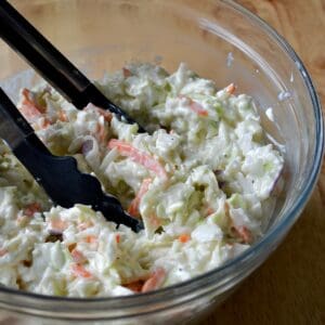 Creamy coleslaw with tongs for serving