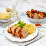 Juicy marinated air fryer pork tenderloin sliced on a plate with rice and broccoli.