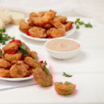 Crispy battered Air Fryer Shrimp on a plate with a dish of dipping sauce.