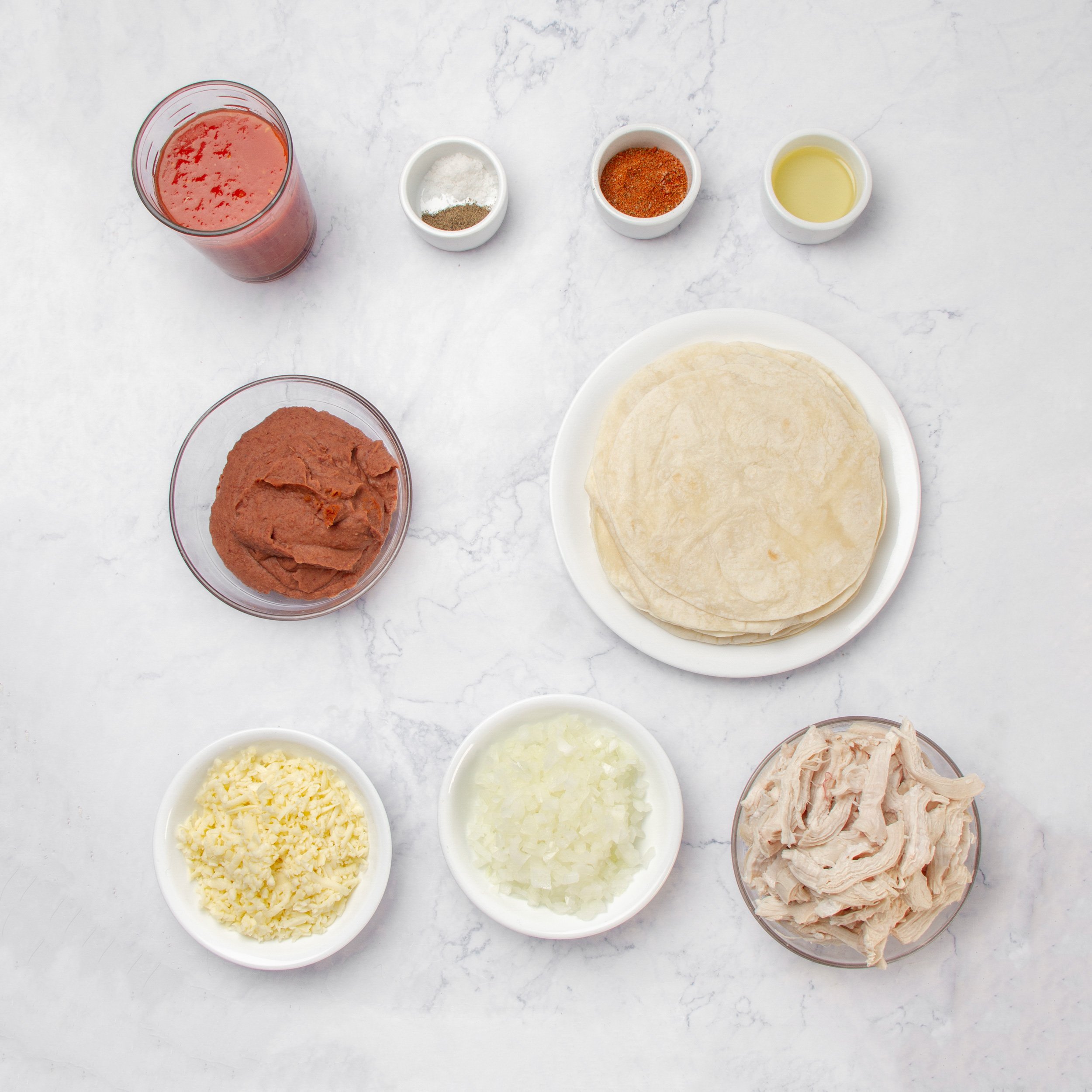 Chicken enchilada ingredients in separate dishes on a counter.