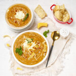 Beautiful and creamy Sweet Potato Soup in two bowls with bread on the side.