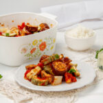 Greek Vegetable Casserole, known as Briam, served on a plate beside a baking dish.