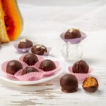 Healthy yet indulgent Chocolate Pumpkin Truffles on a plate with some on a countertop beside it.