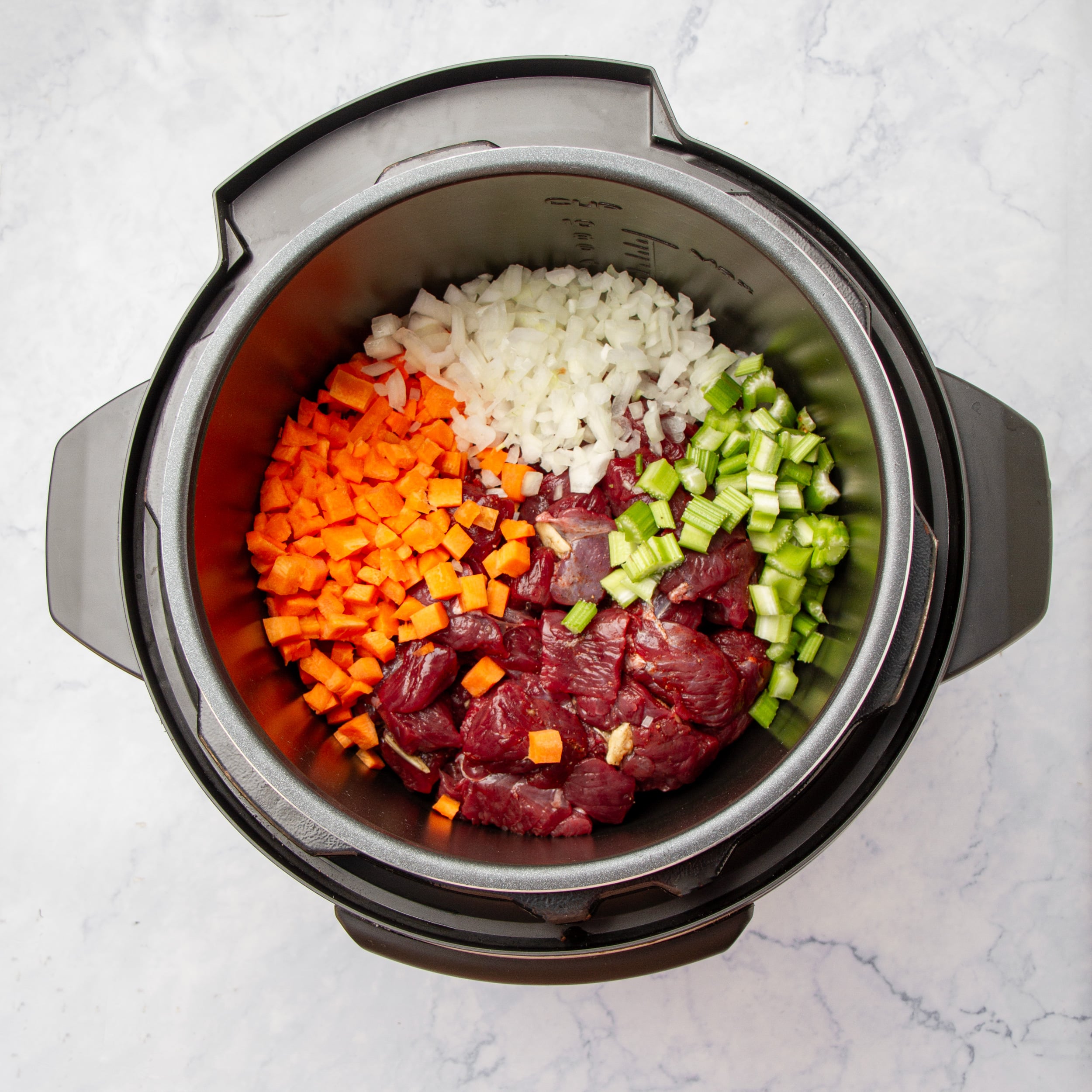Vegetables and raw beef added to the Instant Pot. 