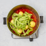 Green beans added to the pan over potatoes and cooked vegetables.