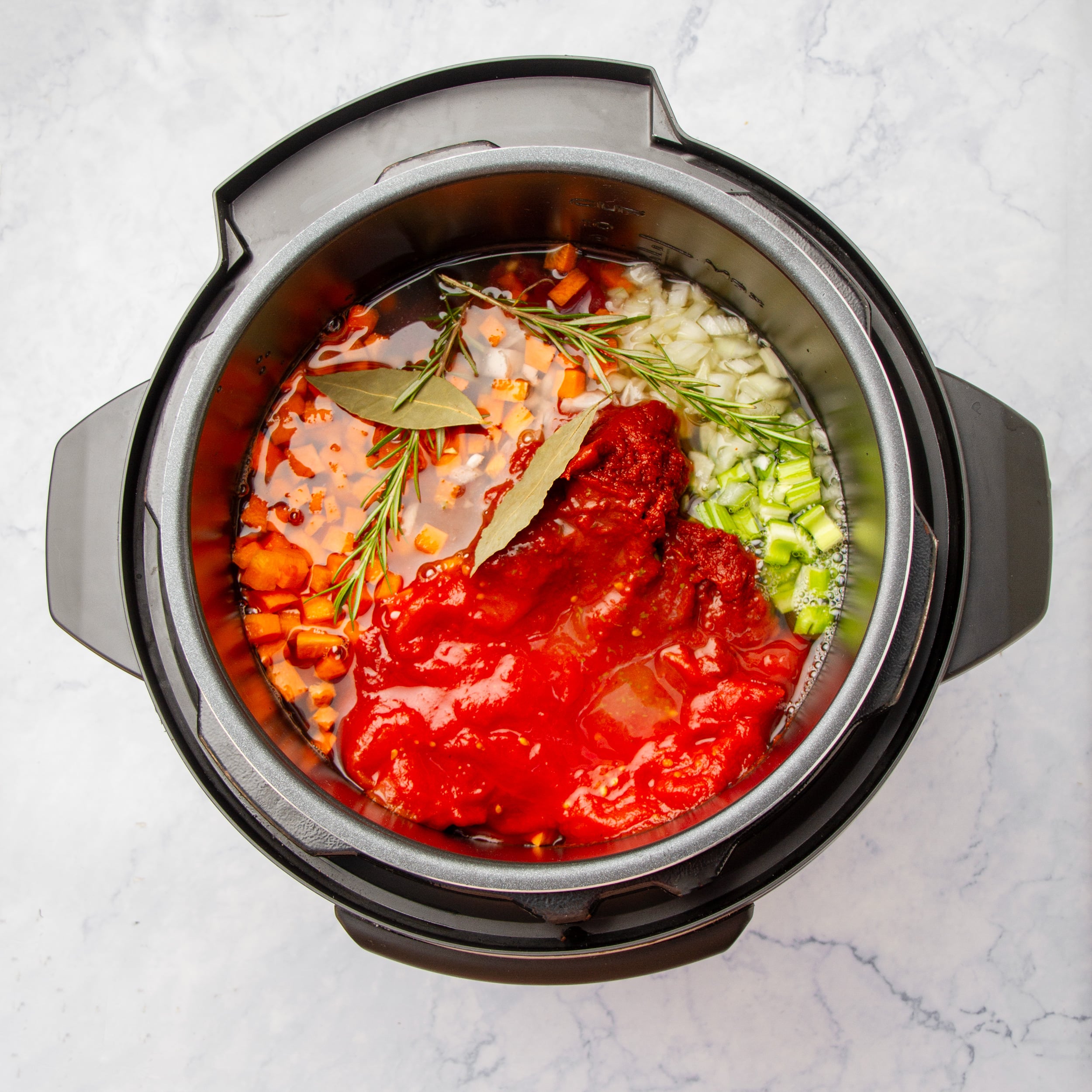 Tomato paste, diced tomatoes, and broth added into the Instant Pot with raw vegetables and meat. 