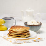 A stack of sweet and satisfying banana omelet on a plate with a bowl of cottage cheese on the side.