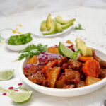 Hearty and aromatic Mexican Beef Stew with fresh cilantro and lime wedges in a bowl.