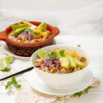 Hearty and delicious White Turkey Chili in a bowl with avocado slices, fresh cilantro, and a lime wedge.