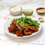 Korean Chicken Bulgogi on a plate with fresh green beans.
