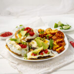 Crispy and satisying Huevos Motuleños with savory toppings on a plate.