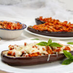 Italian-inspired Baked Stuffed Eggplant on a plate with cheese and extra sauce on the side.