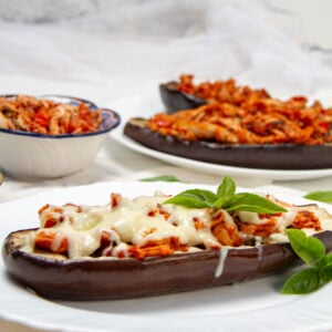 Italian-inspired Baked Stuffed Eggplant on a plate with cheese and extra sauce on the side.