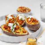 Creamy Baked Turkey-Stuffed Sweet Potatoes on a serving dish with sour cream on top.